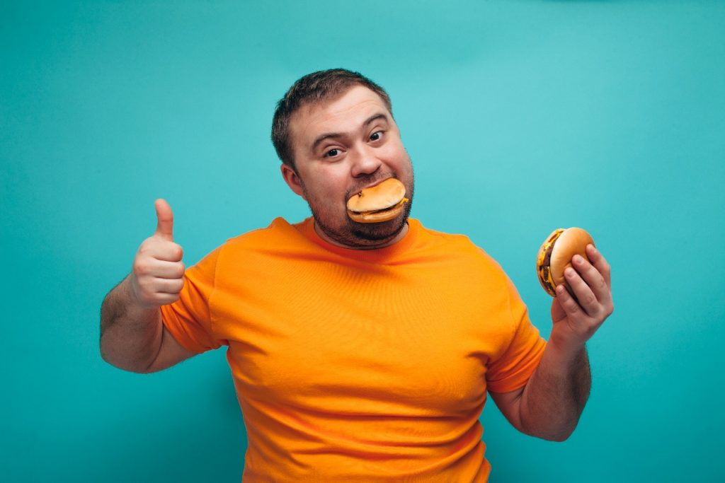 Happy fat man eating burger